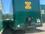 two green semi trucks that are parked in a lot