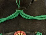 an image of a green hat with a red flower and feathers on it