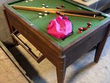 a pool table with two cues on it and a pink bag on the table