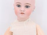 an old wooden doll with a white shirt and blue eyes