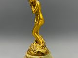 une figurine en or représentant un homme, posée sur un socle en marbre