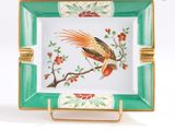 une assiette verte et dorée sur laquelle est représenté un oiseau