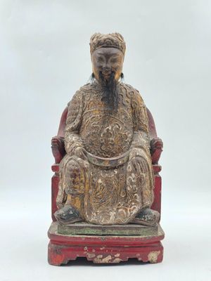 une photo représentant la statue d'un homme assis sur une chaise rouge