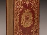 an old book with a red cover and gold decoration