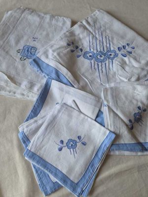 quatre serviettes de table posées sur un lit, ornées d'un motif bleu