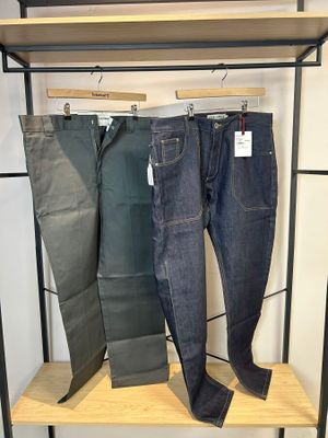 trois paires de jeans suspendues à un portant dans un magasin de vêtements