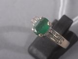 a close up of a ring with a green stone on it