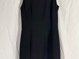 une robe noire suspendue à un cintre sur un drap blanc