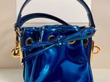 un sac à main bleu posé sur une table, à côté d'une boîte