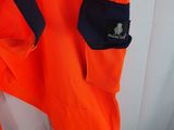 a close up of an orange safety suit hanging on a wall