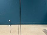 an orange floor lamp with a black base and a red light on top of it