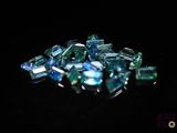 blue and green crystals on a black surface with a black background