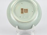 a green plate on a stand on a white surface