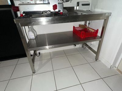 une cuisine avec une table en inox sur laquelle est posé un panier rouge