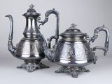 two silver teapots sitting on top of a table next to each other