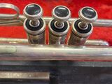a silver trumpet sitting in a case on a carpet