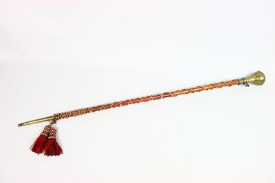 une vieille pipe en laiton dont l'extrémité est ornée d'un pompon rouge