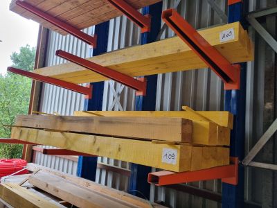 Plusieurs morceaux de bois sont empilés sur une palette devant un bâtiment
