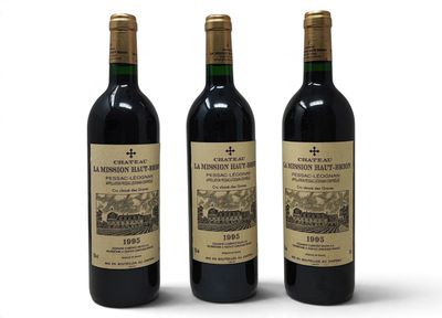 trois bouteilles de vin rouge posées l'une à côté de l'autre sur une surface blanche