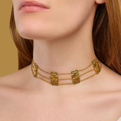 a woman wearing a gold choke necklace with green stones