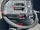 un aspirateur posé par terre, muni d'un tuyau