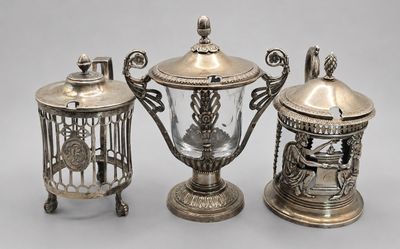 two silverplated teapots and a birdcage with a bird on top