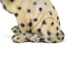 a figurine of a dalmatian dog sitting on a white surface