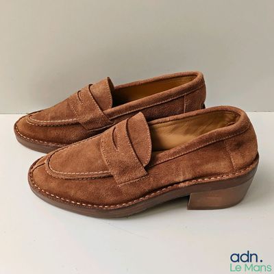 un gros plan sur une paire de chaussures marron posées sur une surface blanche