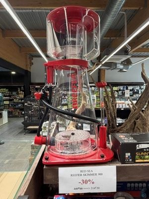 un mixeur rouge posé sur une étagère dans un magasin