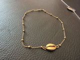a close up of a gold bracelet with a shell on it