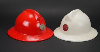 deux casques de pompier rouges et blancs posés l'un à côté de l'autre sur une surface noire