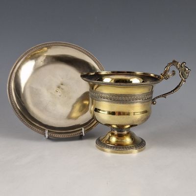une coupe en argent et une assiette en argent posées sur une table