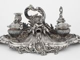une figurine en argent surmontée d'un paon