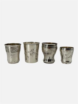 trois verres à shot en argent posés les uns à côté des autres sur une surface blanche