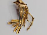 a gold bird brooch on a white surface