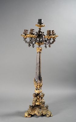 a tall gold and silver candle holder on a stand