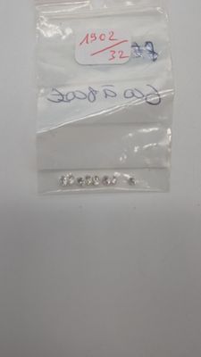 un petit sachet de perles argentées posé sur une surface blanche