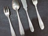 three forks and two spoons on a black surface