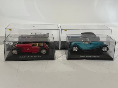 two model cars are in a clear display case on a white surface