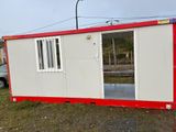 une maison préfabriquée rouge et blanche posée dans l'herbe