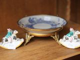deux figurines miniatures posées sur une étagère à côté d'un bol