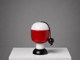 une lampe rouge et blanche posée sur un socle blanc