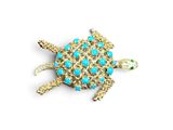 un gros plan d'une broche en forme de tortue ornée de pierres turquoise