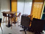 tables and stools in a room with a large window and a wooden floor