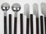 five spoons and five knives on a white surface