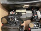 a lot of old cameras sitting on top of a suitcase