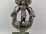 une statue en bronze représentant une femme tenant une couronne, posée sur un socle en marbre