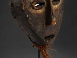 a wooden mask on a stand with a black background