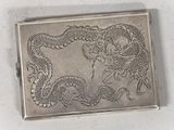 a silver box with a dragon on it on a table