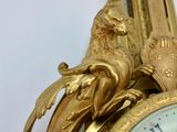 a gold clock with a bird on top of it